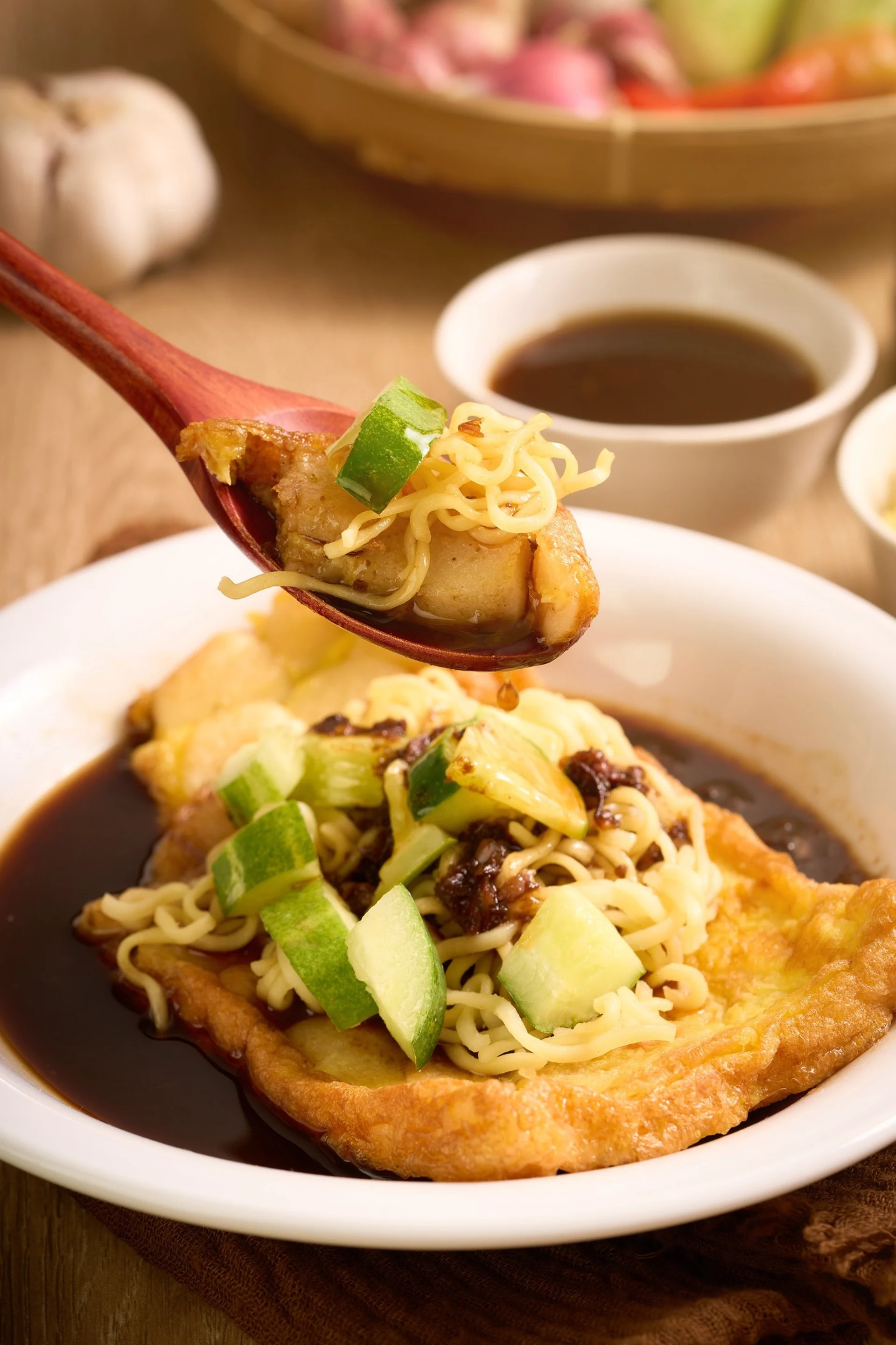 Sendok mengangkat pempek dengan cuko dan mie kuning